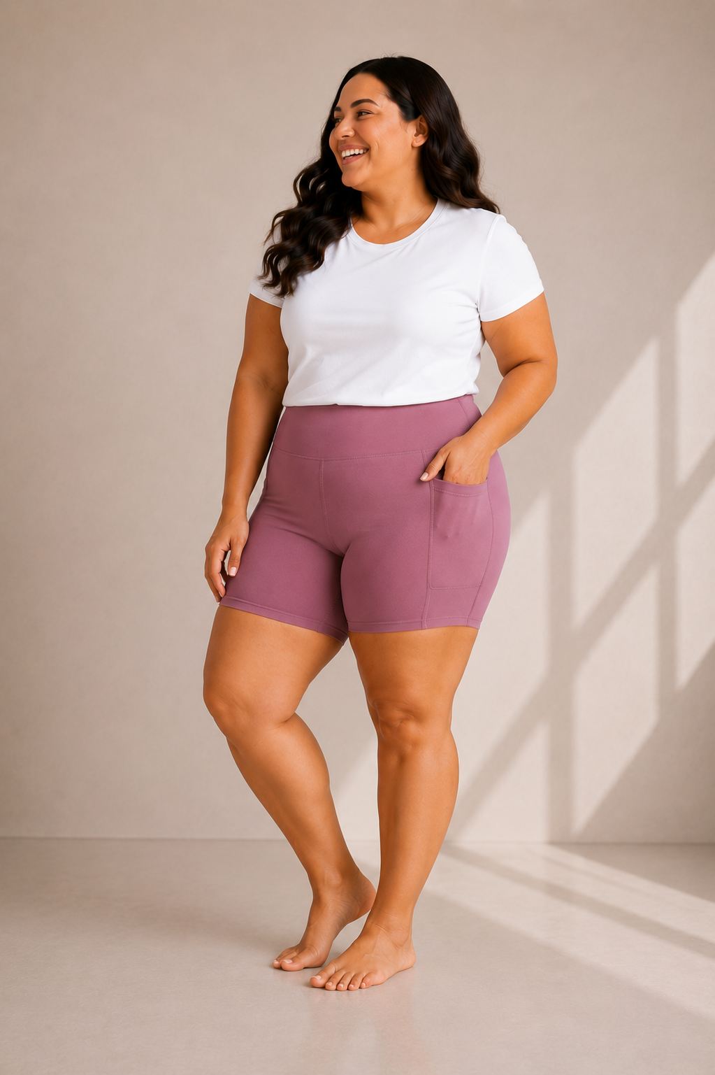 Woman wearing Barefoot & Busy Desert Rose high waisted pocket shorts with a white t-shirt in a bright modern studio.