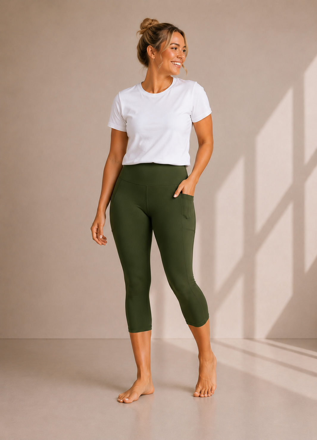 Woman wearing Olive Grove high waisted pocket capri leggings by Barefoot & Busy with a white t-shirt in a studio setting