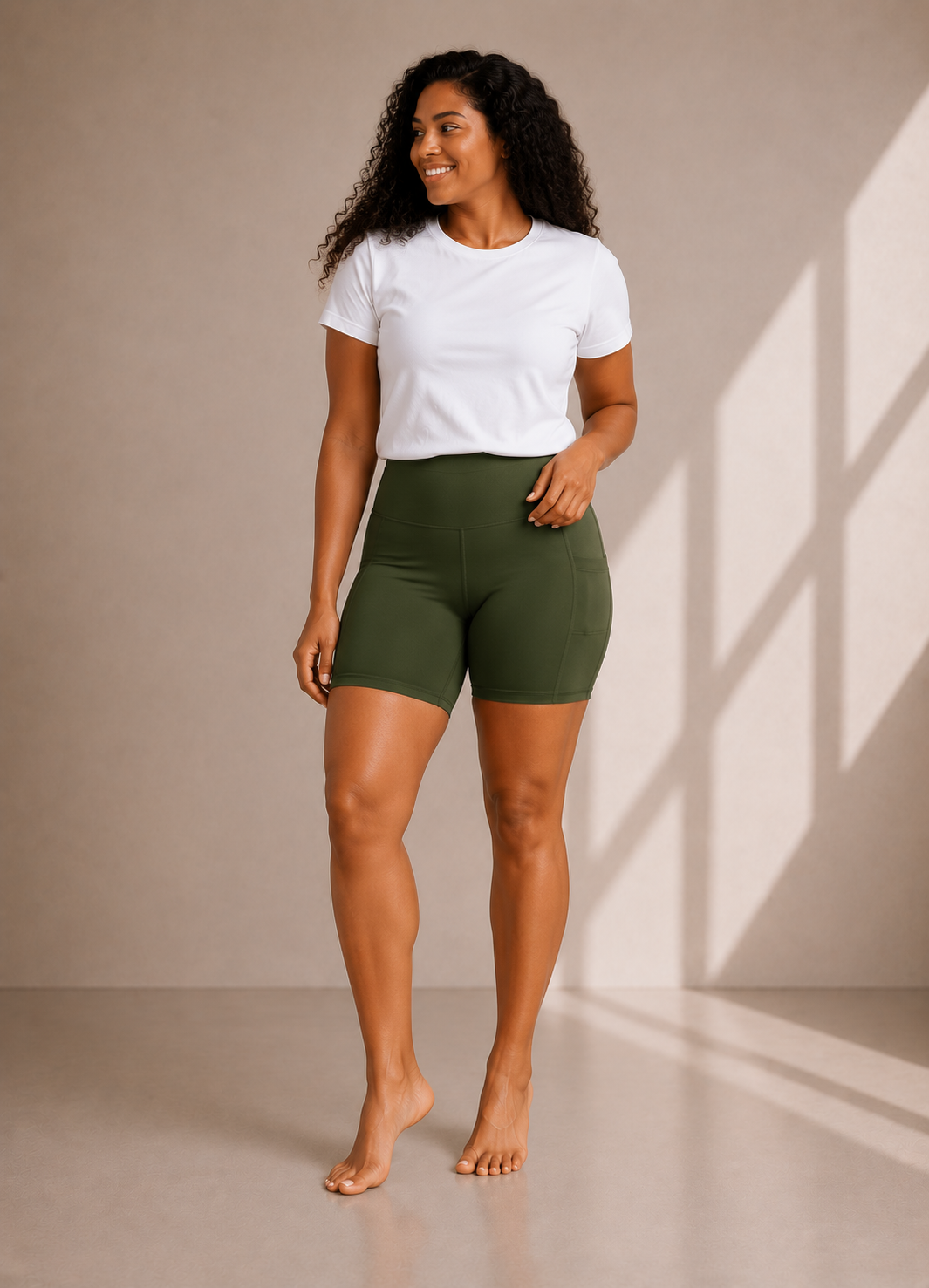 Woman wearing Olive Grove high waisted pocket shorts by Barefoot & Busy with a white t-shirt in a studio setting