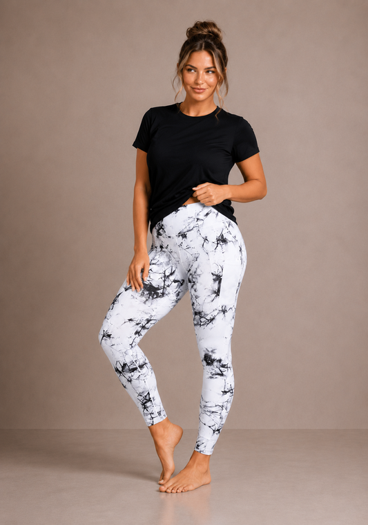 Woman wearing Barefoot & Busy White Marble high waisted pocket leggings with a black t-shirt in a bright modern studio.