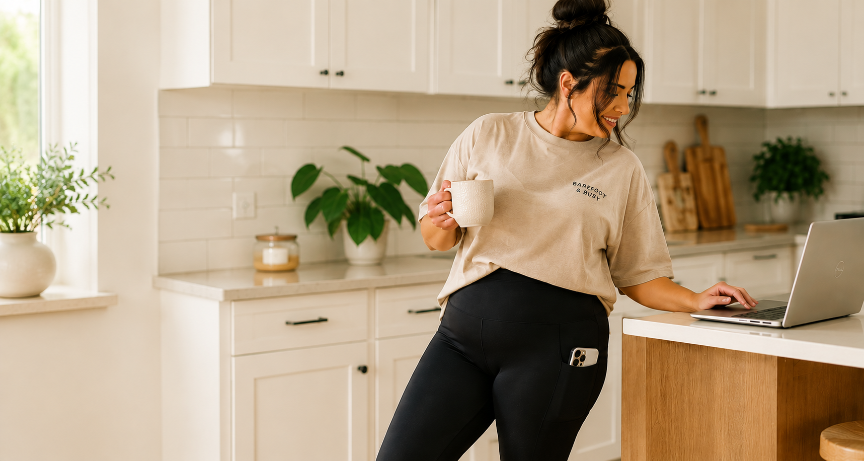 Woman wearing Barefoot & Busy high-waisted leggings with deep pockets and a relaxed oversized t-shirt, standing in a modern home. Comfortable everyday leggings designed for busy women.